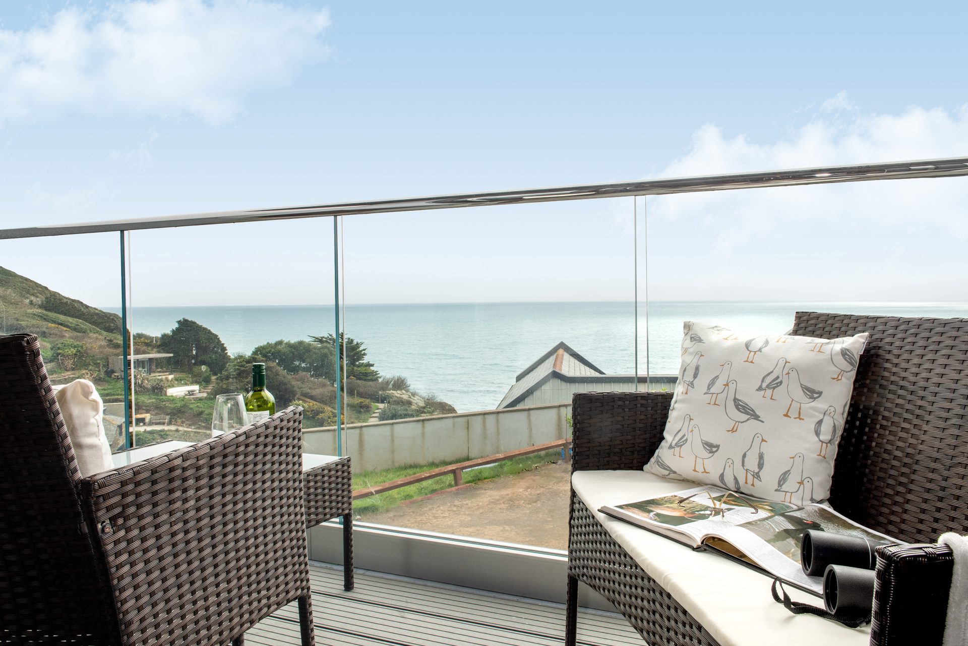 Low angled view from balcony overlooking the sea, with seating either side of balcony